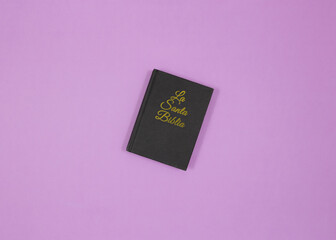 Top view of a small black Santa Biblia. Purple background