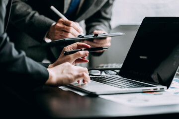 Close up of businesspeople discussing and using a laptop with analysis chart graph business report at the workplace, investor trading stock market, project planning, financial and investment concept.