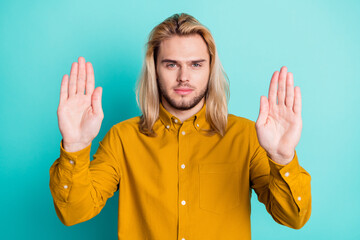 Photo of young guy show hands no stop sign denial rejection forbidden isolated over teal color...