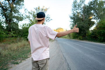 hitchhiker standing on the roadside with a thumb up waiting for the car