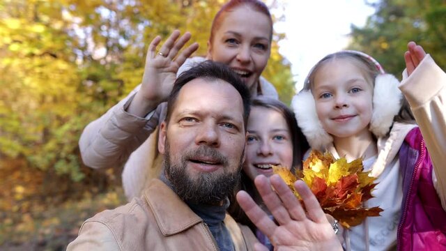 a man and a woman with children take pictures of themselves on camera in the autumn forest, a family on a walk in the park