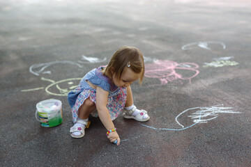 Naklejka premium Overhead shot of a little girl scribbling in colourful chalk on pavement