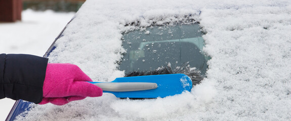 Hand using brush and remove snow from car and windscreen. Problems in winter