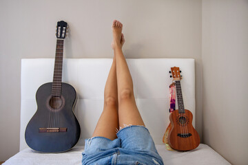 Mujer tumbada en la cama junto a su guitarra y ukelele