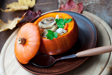 Baked pumpkin stuffed rice, carrots, pepper and mushrooms with parsley on brown plate on dark brown background. Healthy vegetarian food