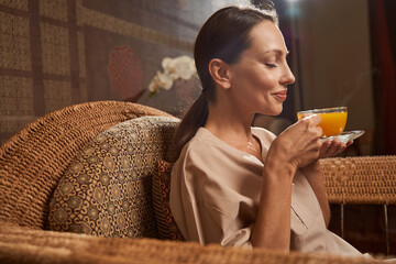 Smiling woman inhaling aroma of hot herbal drink