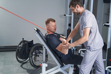 Therapist help patient with disability doing exercises at rehab center