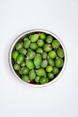 A bowl of green feijoa fruits on the white background in the middle of photo. Vertical view. Flatlay.