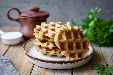 Thick potato waffles on a white plate on a wooden table for a light snack. Close-up