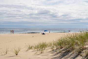 Scenic beach scene with joggers and people under beach umbrella at the Jersey  shore
