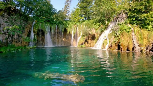Plitvice lakes and waterfalls, Croatia. View from tourist perspective. Walking near lake and waterfall in pure fresh nature. National nature park, famous travel destination.