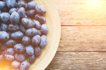 Plate with plums on a rustic wooden background, top view.