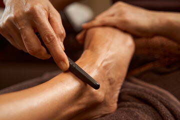 Practitioner using reflexology stick during Thai foot massage session