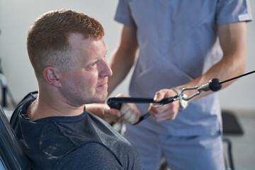 Resolute young man with injury train arm, hand on weight lift machine