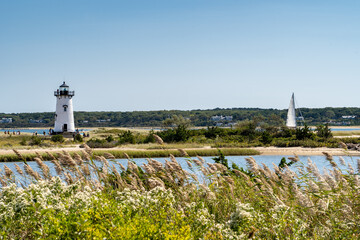 Edgartown Harbor Light lighthouse with wild grass and sailboat on Martha's Vineyard, Massachusetts