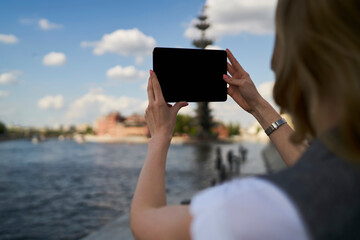 Female generation Z using blank touch pad device with copy space area for media advertising, back view of millennial tourist clicking image pictures or shooting video content on digital tablet