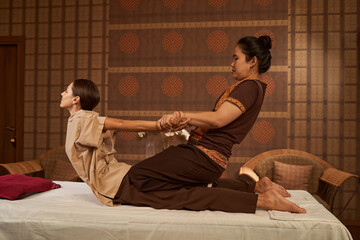 Practitioner stretching her client back muscles during Thai massage session