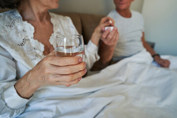 Senior citizen talking pill while holding glass of water