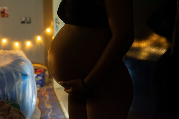 Scenes of a home birth, the pregnant woman caressing her belly in a dark room