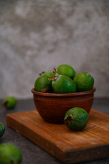A bowl of green feijoa on the grey background. Vertical view.
