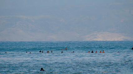 Obraz premium Surfers in search of a wave. Surfers in the sea are waiting for a wave.