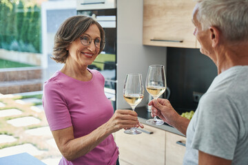 Excited senior woman clinking glasses with her man