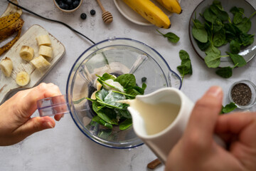 Cooking, preparring green spinach, banana and blueberry smoothie. Female hands, top view. Step by step recipe.