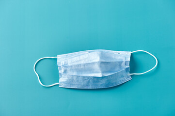 Face mask over blue background. Protective raspiratory mask for spreading virus. Close up, copy space, top view