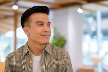 Portrait of handsome young man at coffee shop thinking - 466754439