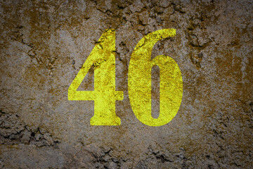 Number forty six. Yellow enumeration on the old concrete surface. Number 46 is related to legacy, knowledge, entrepreneurial skills and leadership. Written with overlapping tones.