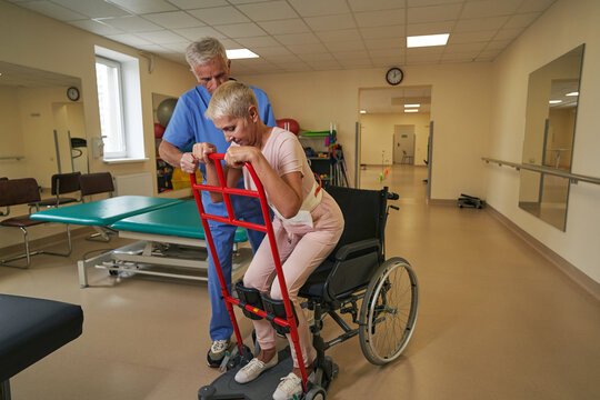 Professional physiotherapist assists female patient in recovery at rehab center