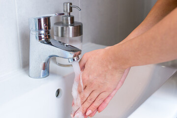 Woman use soap and washing hands rubbing with soap under the water tap. Hygiene new normal concept to stop spreading coronavirus or influenza virus.Woman use soap and washing hands under the water tap