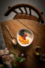 granola with yogurt and berries on a wooden table with chair