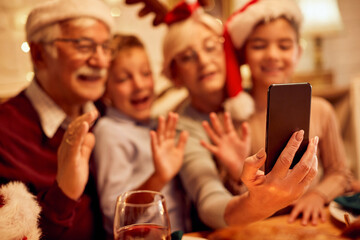 Close-up of grandparents with grandchildren make video call over smartphone on Christmas.