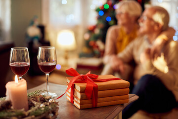 Close-up of books tied with red ribbon with senior couple in the background on Christmas.