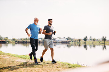 Happy athletic father and son run while exercising together in nature.
