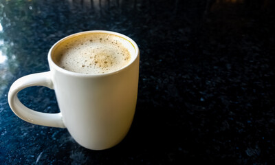white ceramic cup of hot milk coffee on a granite stone table. Copy space