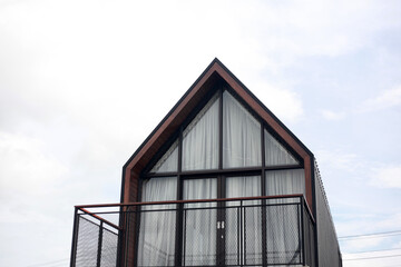 Modern minimalism log house against bright blue sky with white clouds. Copy space