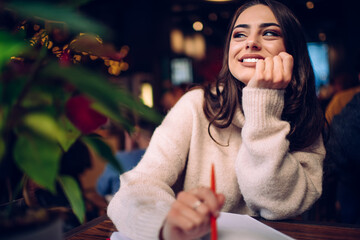 Dreamy woman with pen sitting in cafe