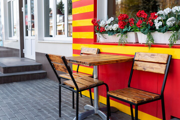 Empty wooden table and chairs in a bright stylish street cafe.