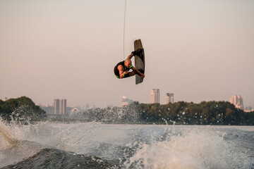 Energy guy holds rope and jumping and flip with wakeboard.