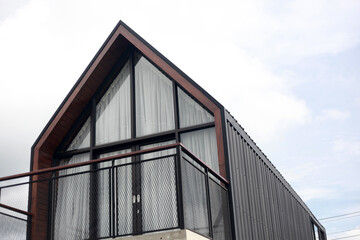 Fototapeta na wymiar Modern minimalism log house against bright blue sky with white clouds. Copy space