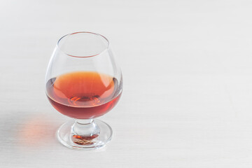 A glass of cognac or brandy on a light background. Empty space for the copy space on the right