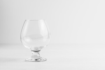 An empty glass glass for cognac or brandy on a light background is shifted to the left Copy space