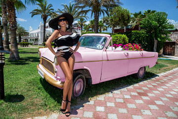 Bikini fashion. Beautiful sexy blonde woman in colorful swimsuit near the pink car on Cuba Havana....
