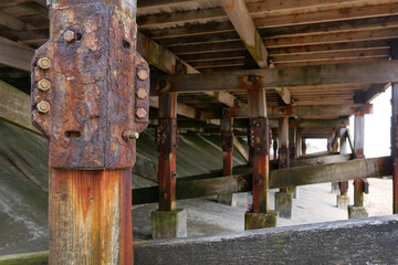 Fototapeta na wymiar Underneath of wooden pier showing rusty nuts and bolts and staining