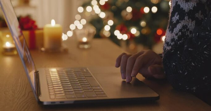 Close-up hand enter gift card on web page sending Merry Xmas eve wishing text on e-mail working on digital tablet laptop at home. Good warm time cozy night winter season with tree light inside house.