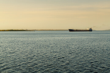A barge in the distance on the water of a large navigable river.