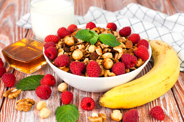 Granola, fresh raspberries and banana for breakfast on the table. Healthy breakfast in the morning. Сlose-up.