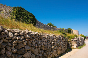 Fototapeta na wymiar Part of the medieval town walls of the historic hill village of Vrbnsk on Krk Island in the Primorje-Gorski Kotar County of western Croatia 